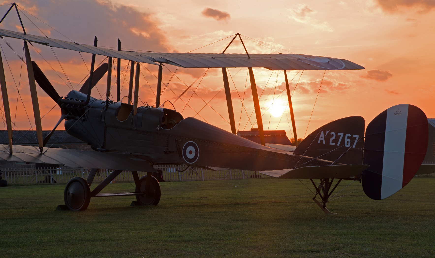 BE2e A2767 silhouetted against a sunset, the low sun flaring through its bracing wires.